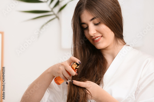 Young woman applying conditioner on beautiful long hair in bathroom photo