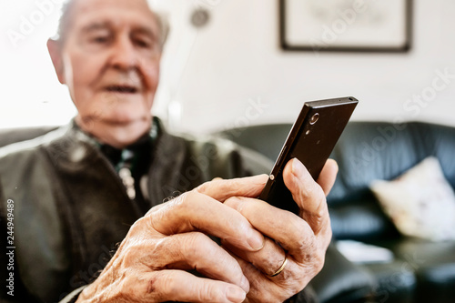 Senior surft zuhause mit seinem smart phone im Internet