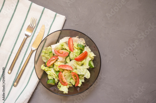 healthy salad, vegetable, tomatoes, cucumbers, iceberg, Cutlery, kitchen towel, grey background. Copy space. Vegetarian