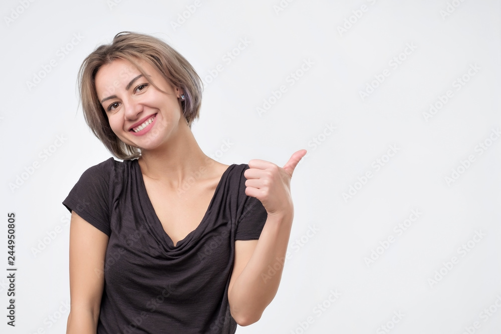 Smiling pretty young woman showing thumbs up Smiling pretty young woman showing thumbs up
