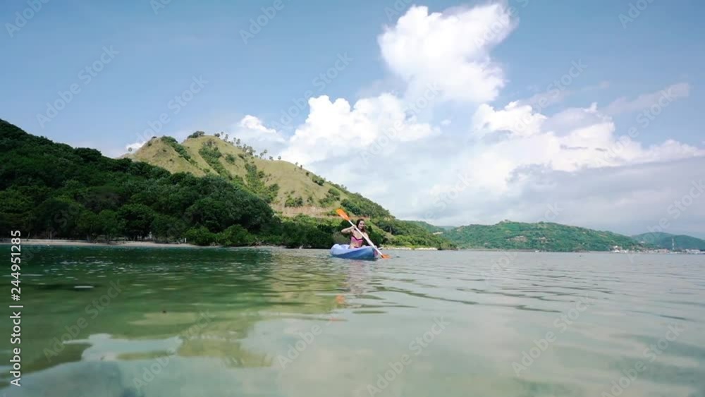 woman paddling with a double-bladed paddle a canoe on the sea during summer vacation in Flores Island, Indonesia woman paddling with a double-bladed paddle a canoe on the sea during summer vacation in Flores Island, Indonesia