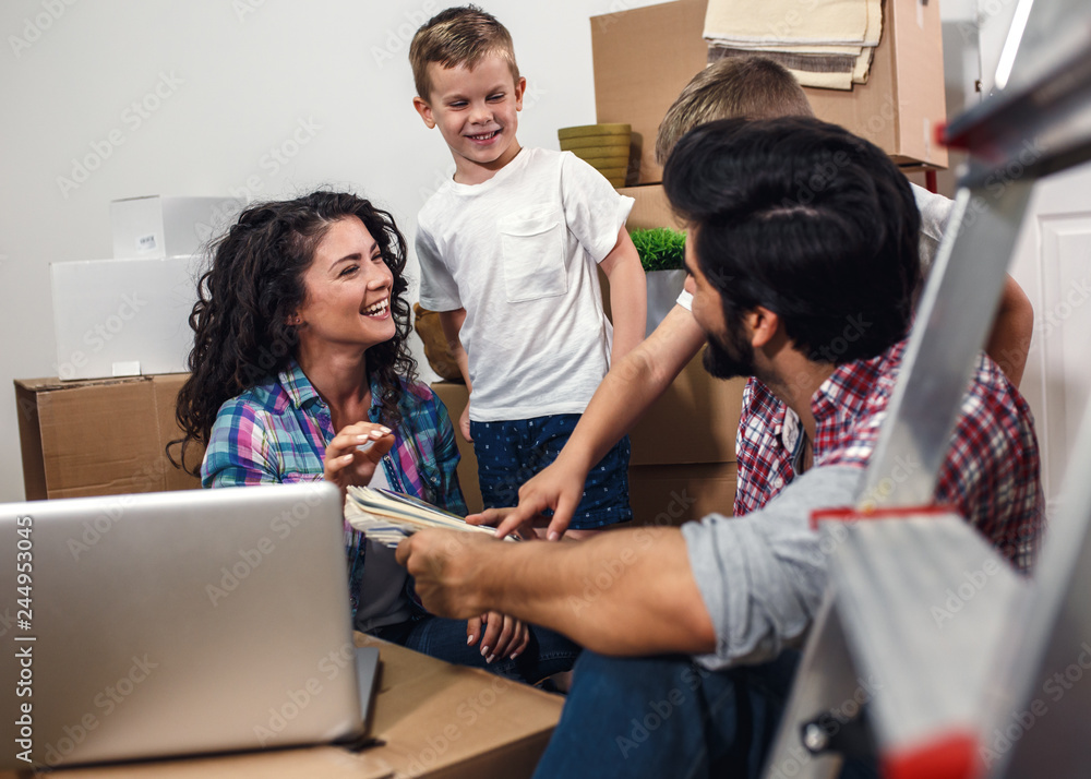 Happy young family having fun while moving into their new home. They sitting on the floor and choosing colors for the walls. Happy young family having fun while moving into their new home. They sitting on the floor and choosing colors for the walls.