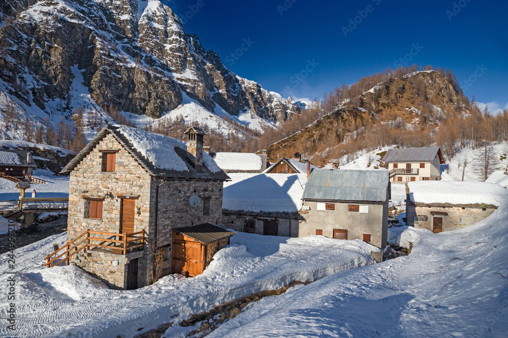 Panoramic view of the sunny snow-covered landscape of the village of Crampiolo, above the Alpe Devero in Piedmont, Italy.