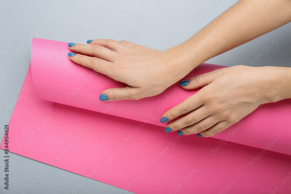 Female hands with beautiful manicure and paper roll on color background Female hands with beautiful manicure and paper roll on color background