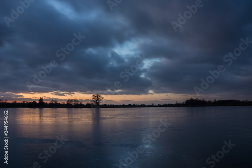 Cloudy sky after sunset, over a frozen lake