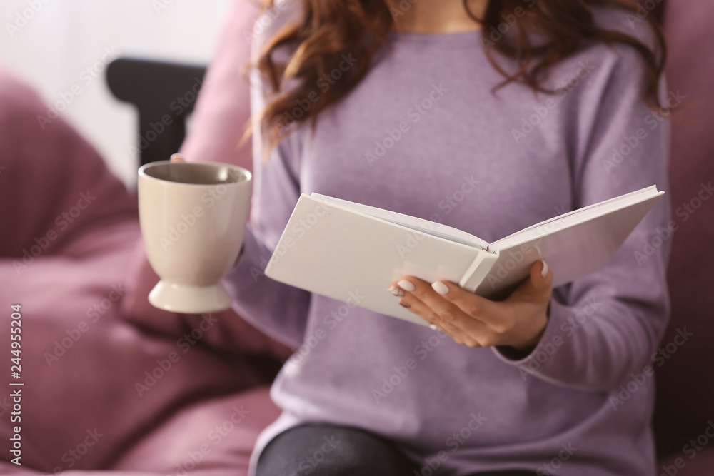 Beautiful young woman drinking coffee while reading book at home Beautiful young woman drinking coffee while reading book at home