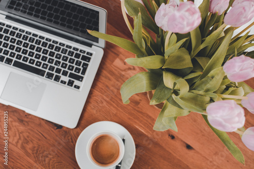 Arbeitsplatz Homeoffice Notebook Laptop auf Tisch Schreibtisch mit Blumen Tulpe und Tasse Kaffee