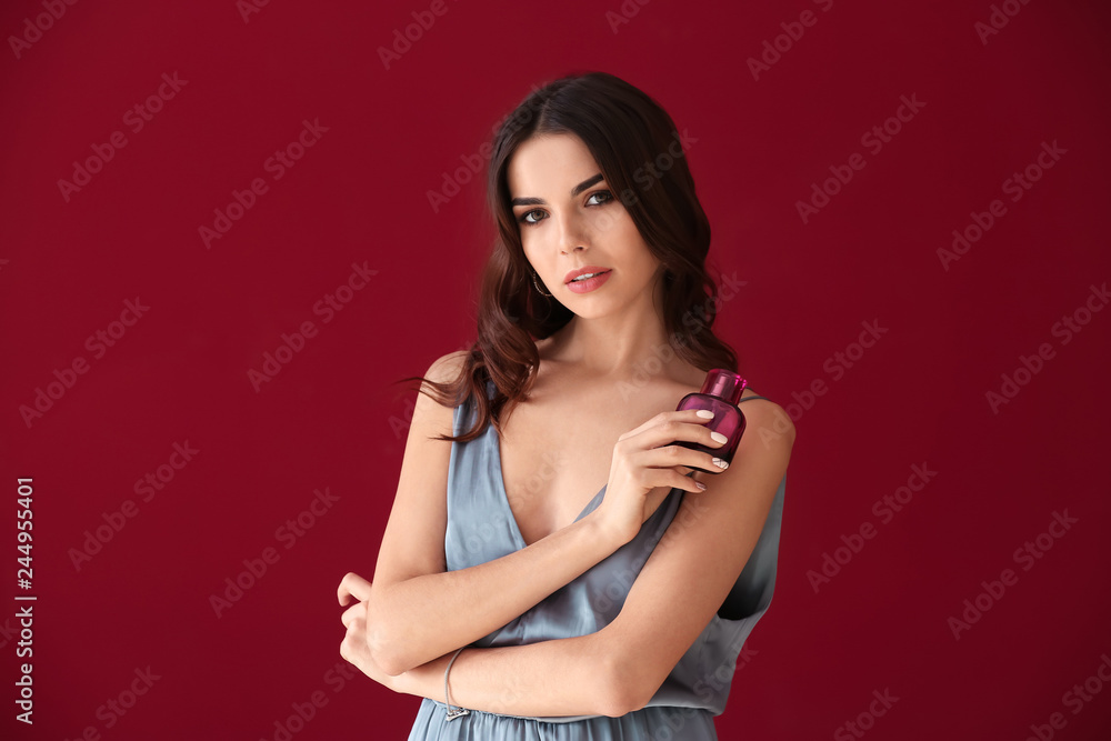 Beautiful young woman with bottle of perfume on color background Beautiful young woman with bottle of perfume on color background
