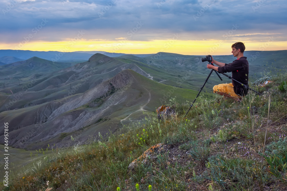 Obraz premium Professional photographer using a tripod, taking a photo of a mountain landscape at sunset
