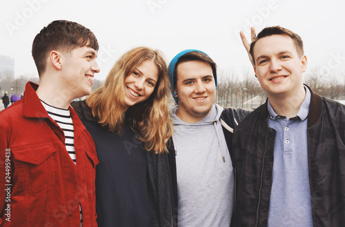 group of four young teenage friends posing arm in arm - fun portrait with bunny ears