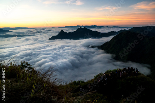 Tourists are looking at sunrise and sea of fog view on phu chi fa mountain area and national forest park in chiang rai, Thailand.