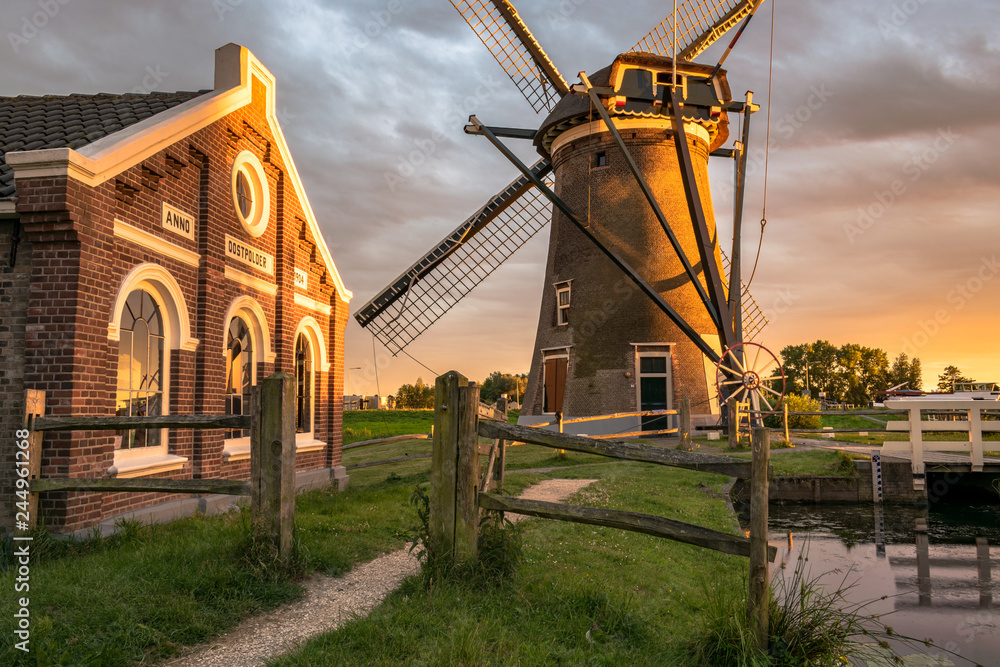 Windmill `Mallemolen` and pumping station in Gouda, Holland at sunset. 