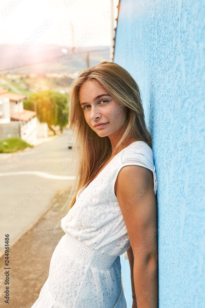 Pretty blond woman against blue wall, portrait