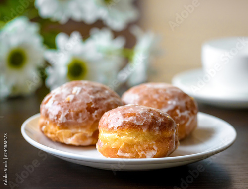 Donuts on a white plate with flower on the table