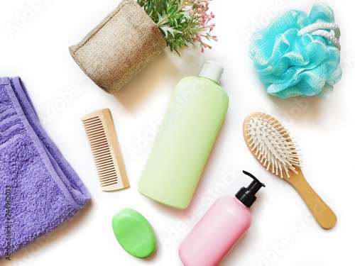 Purple terry towel, green shampoo bottle, pink liquid soap package, blue sponge and wooden hair brushes. Flat lay still life organic bath products, natural cosmetics for skin and hair care