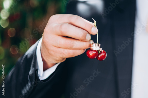 groom holds cherry. soft focus