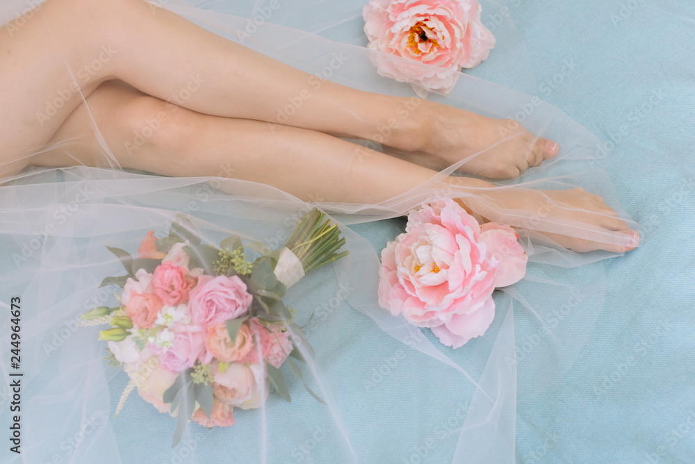Women's feet. Next bouquet of flowers lying on the sofa. Women's feet. Next bouquet of flowers lying on the sofa.