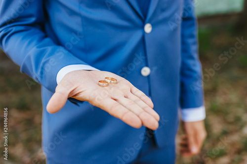 Valokuva groom holds wedding ring on palm. soft focus