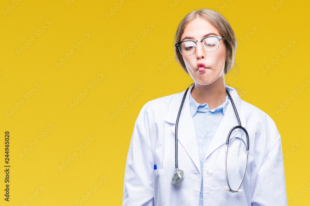 Beautiful young blonde doctor woman wearing medical uniform over isolated background making fish face with lips, crazy and comical gesture. Funny expression. Beautiful young blonde doctor woman wearing medical uniform over isolated background making fish face with lips, crazy and comical gesture. Funny expression.