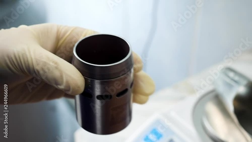 Close up of hands in medical gloves putting chemical powder from chemical scoop to small metal container at laboratory. Hands putting white reagent into chemical receptacle, science conceept. photo