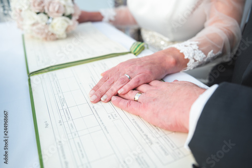 a bride and groom signing a dummy register at a wedding while displaying wedding rings