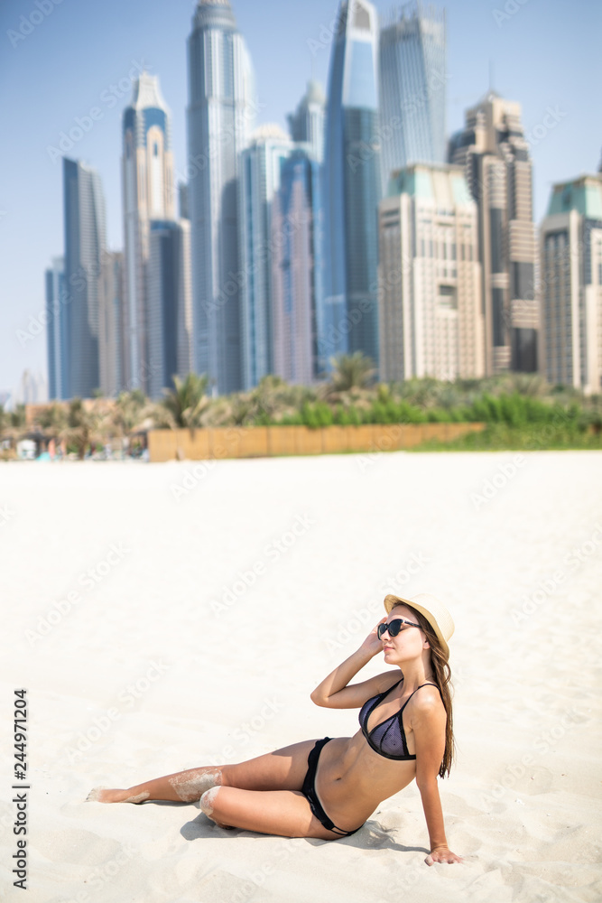 Sexy beautiful woman lying relaxing and sunbathing in bikini on sea background and palm tree. Panoramic view from JBR beach in Dubai, UAE. United Arab Emirates famous tourist destination. Sexy beautiful woman lying relaxing and sunbathing in bikini on sea background and palm tree. Panoramic view from JBR beach in Dubai, UAE. United Arab Emirates famous tourist destination.