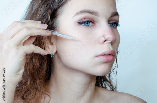  Beautiful young woman with piercing holding a serum pipette.