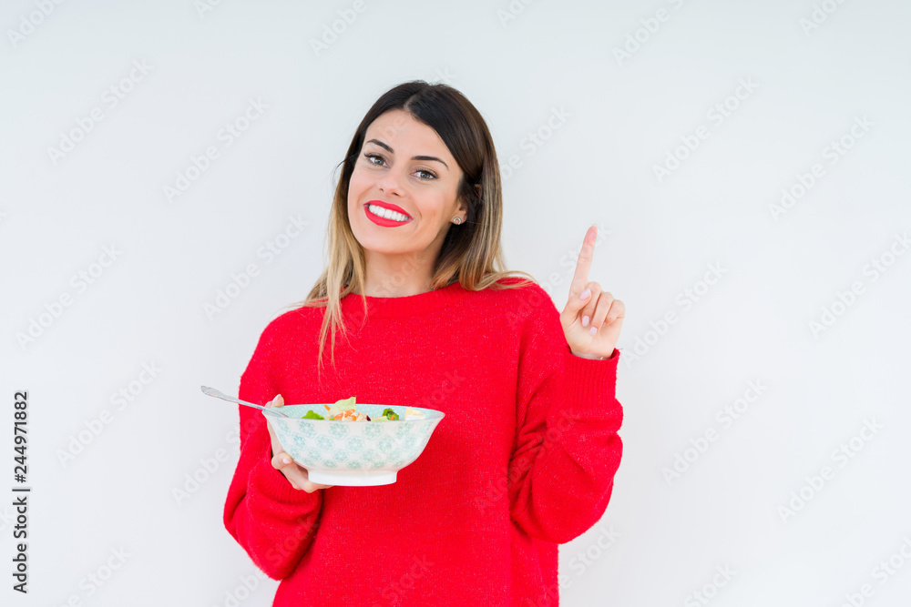 Young woman eating fresh healthy salad over isolated background very happy pointing with hand and finger to the side Young woman eating fresh healthy salad over isolated background very happy pointing with hand and finger to the side
