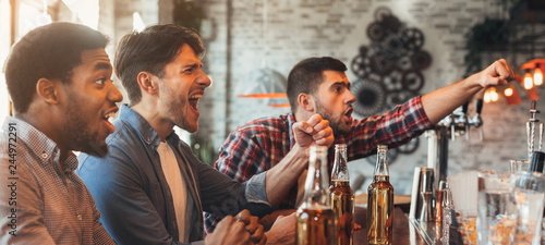 Diverse friends watching football game in bar