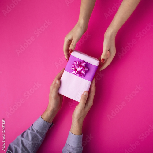 man gives a girl a gift from hand to hand,box wrapped in decorative paper with a bow background, the concept of holidays, love and relationships, top view © fantom_rd