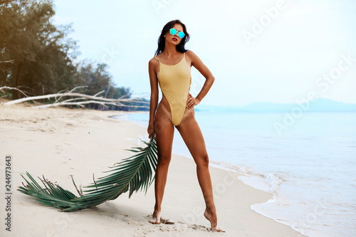 incredibly beautiful sexy girl models in a bikini on the sea shore of a tropical island with palm leaf, blonde brunette, bronze tan, travel summer vacation, fashion style