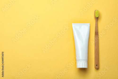 Blank tube of toothpaste and brush on color background, top view with space for text photo