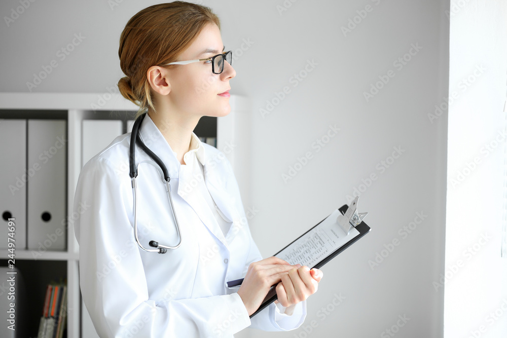 Doctor woman at work. Portrait of female physician using clipboard at hospital office. Medicine and healthcare concept Doctor woman at work. Portrait of female physician using clipboard at hospital office. Medicine and healthcare concept