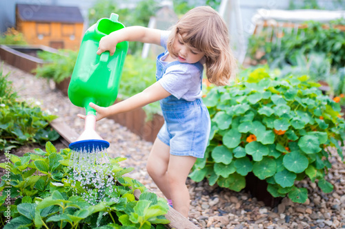 Adorable girl watering plants in the garden
