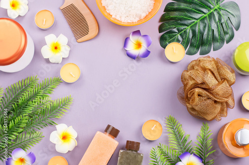 Spa and body care products flat lay. Body scrub, bath salt, moisturizing lotion, candles and leaves on wooden background