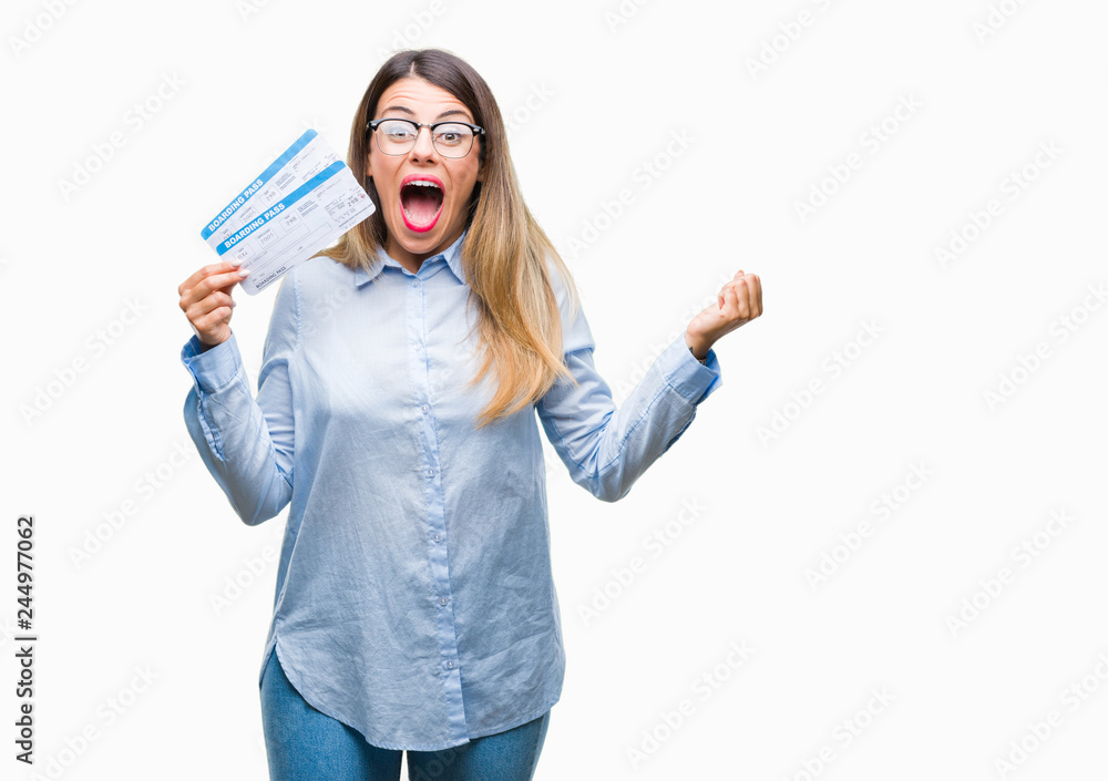 Obraz premium Young beautiful woman holding boarding pass over isolated background very happy and excited, winner expression celebrating victory screaming with big smile and raised hands