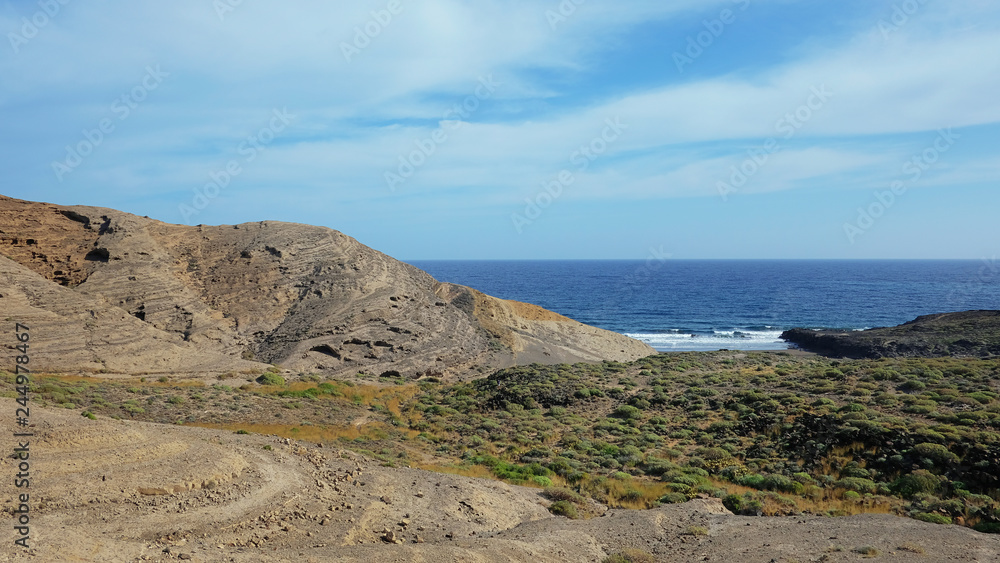Mountain Pelada, locally known as Montana Pelada, an arid volcanic cone formed of fossilized sand dunes, situated at one end of El Medano surf resort in south of Tenerife, Canary Islands, Spain Mountain Pelada, locally known as Montana Pelada, an arid volcanic cone formed of fossilized sand dunes, situated at one end of El Medano surf resort in south of Tenerife, Canary Islands, Spain