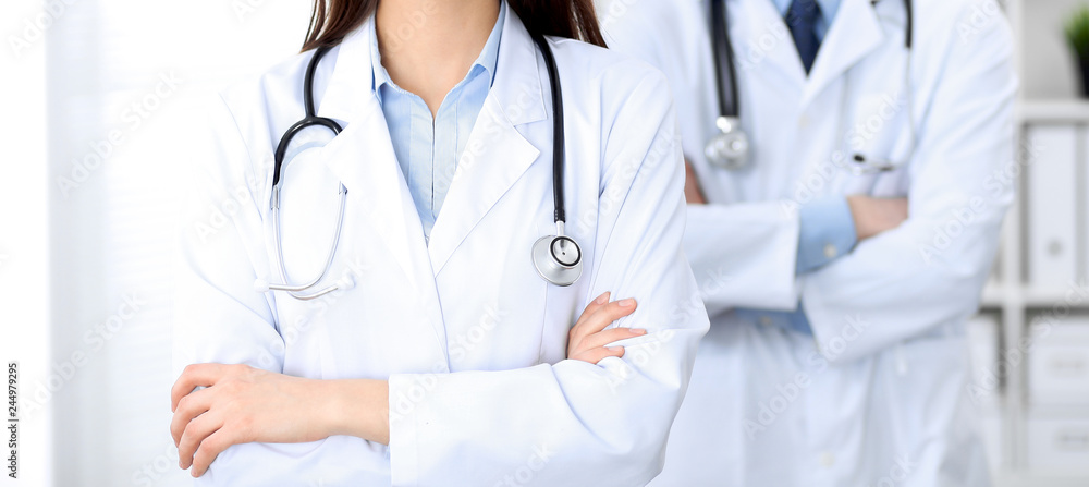 Female doctor with stethoscope standing upright with crossed arms, unknown physician at work. Medicine concept Female doctor with stethoscope standing upright with crossed arms, unknown physician at work. Medicine concept
