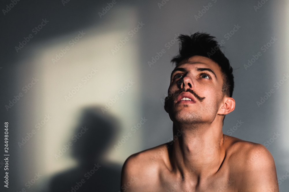 Young shirtless man in despair by the window Young shirtless man in despair by the window