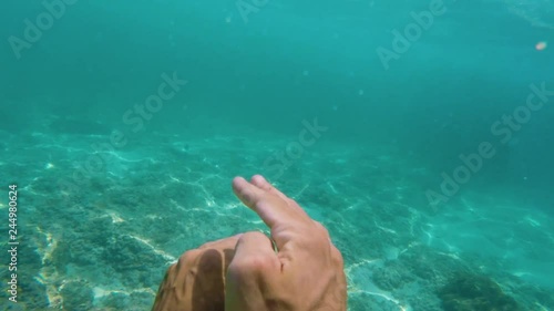 man swims underwater in oceaan among coral reefs. first person view