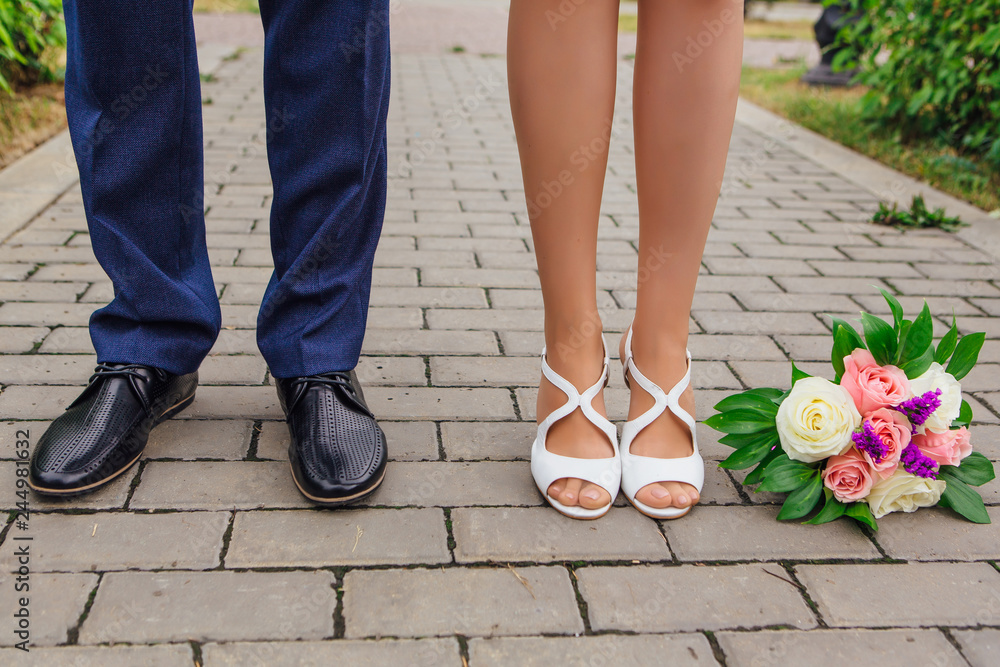 Feet of groom and bride with wedding bouquet