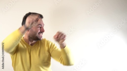 Attractive adult bearded husband in plaid shirt dancing hip hop showing yo gesture with hands, standing against gray wall. Dad tries convince teenage daughter he knows what is in trend. photo