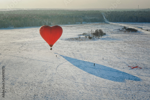 red heart shape hot air balloon on the snow field