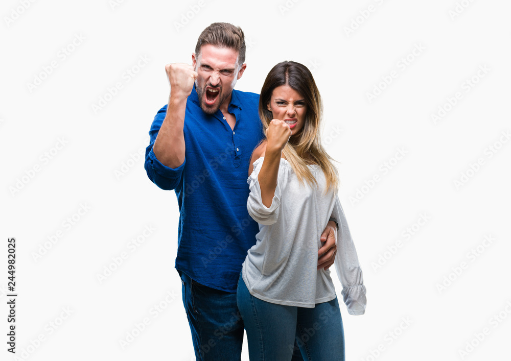 Fototapeta premium Young couple in love over isolated background angry and mad raising fist frustrated and furious while shouting with anger. Rage and aggressive concept.