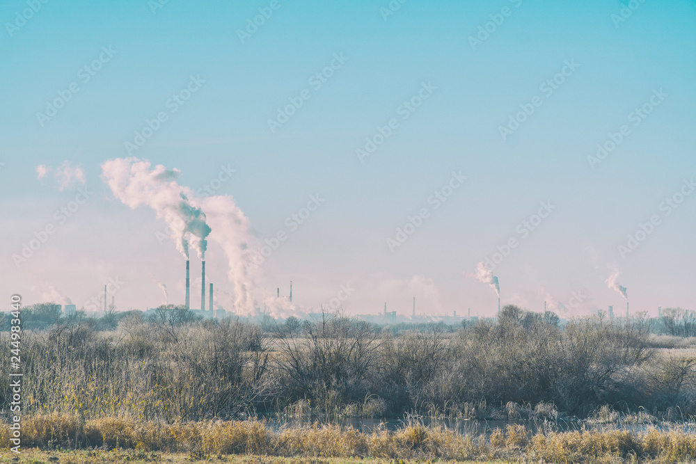 Modern landscape with factory pipes at a distance from which smoke is polluting air