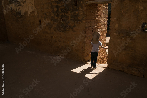 A boy in a cowboy hat in the doorway of ancient ruins