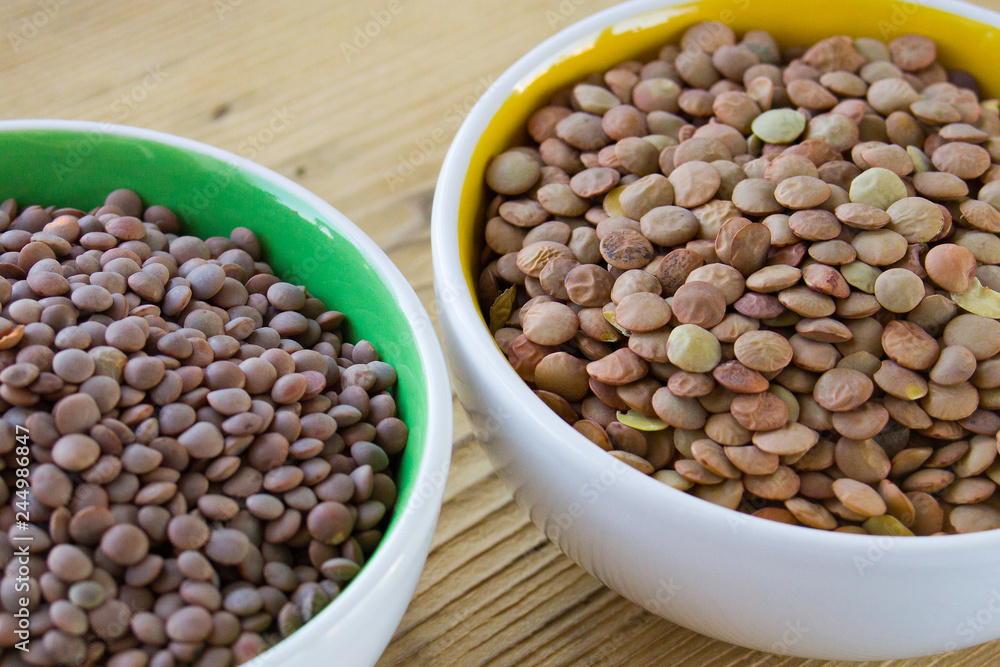 red and green lentils in white plates on a wooden board red and green lentils in white plates on a wooden board