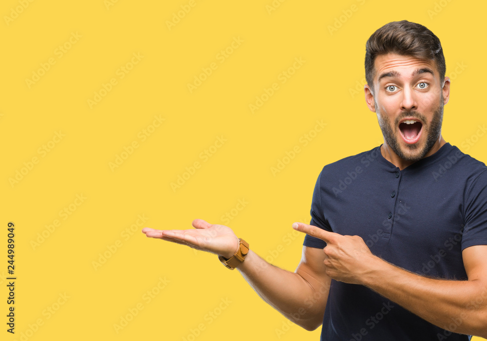 Young handsome man over isolated background amazed and smiling to the camera while presenting with hand and pointing with finger. Young handsome man over isolated background amazed and smiling to the camera while presenting with hand and pointing with finger.