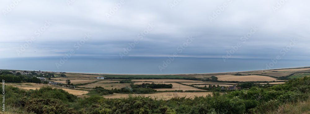 South Dorset coastline near Weymouth, England. With meadows, clouds and deep blue sea. Panorama and banner
