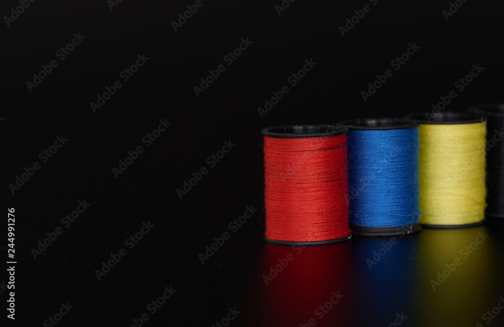 Hilos de coser sobre fondo negro, en diferentes colores, azul, rojo Hilos de coser sobre fondo negro, en diferentes colores, azul, rojo
